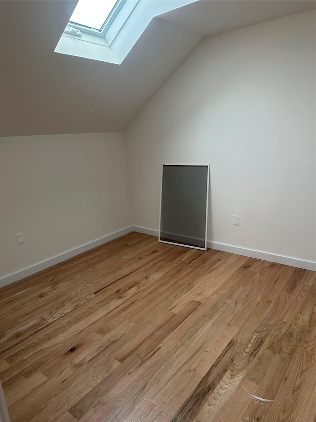 bonus room with light wood-type flooring and vaulted ceiling with skylight