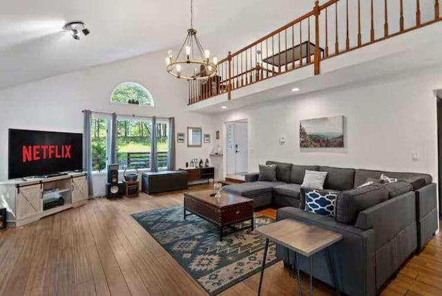 living room with hardwood / wood-style floors, high vaulted ceiling, and an inviting chandelier