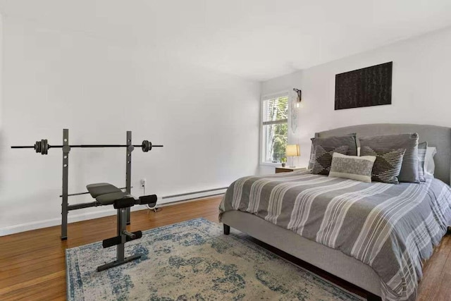 bedroom featuring hardwood / wood-style floors and a baseboard heating unit