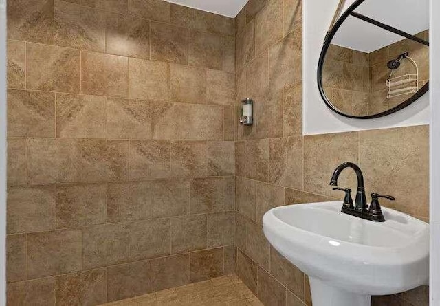 bathroom featuring tiled shower, tile walls, and sink