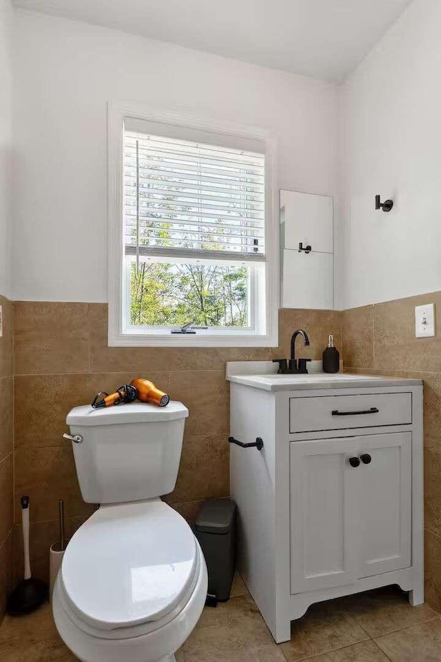 bathroom featuring tile patterned flooring, vanity, toilet, and tile walls