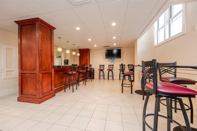 bar with light tile patterned floors and hanging light fixtures