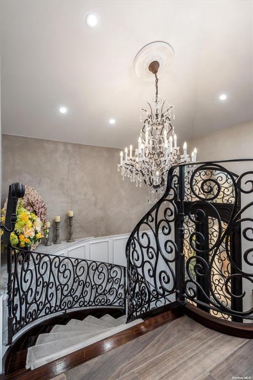 stairway featuring hardwood / wood-style flooring and a chandelier