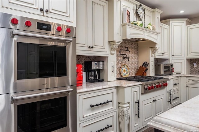 kitchen featuring light stone countertops, appliances with stainless steel finishes, tasteful backsplash, and white cabinetry