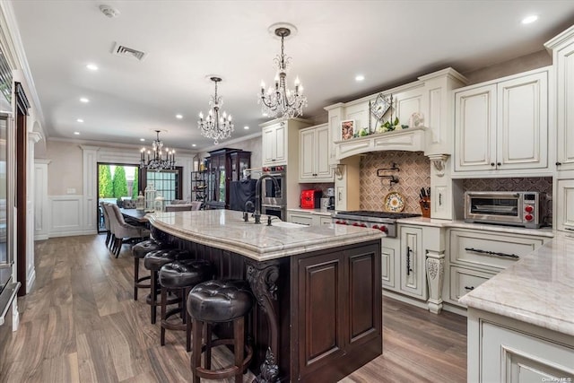 kitchen with pendant lighting, a breakfast bar, crown molding, and an island with sink