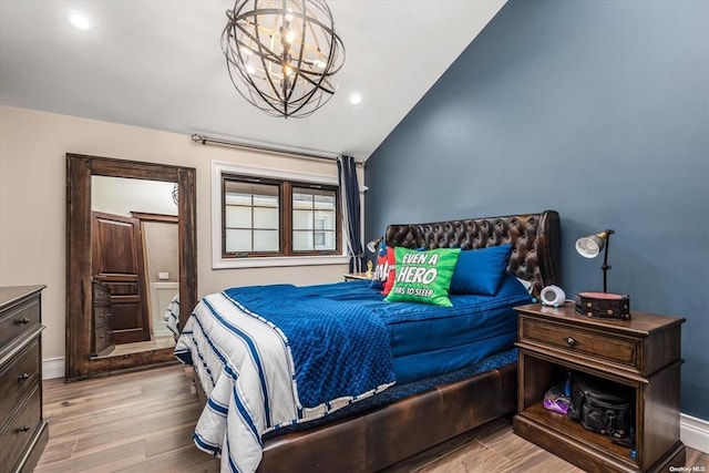 bedroom with an inviting chandelier, vaulted ceiling, and light hardwood / wood-style flooring