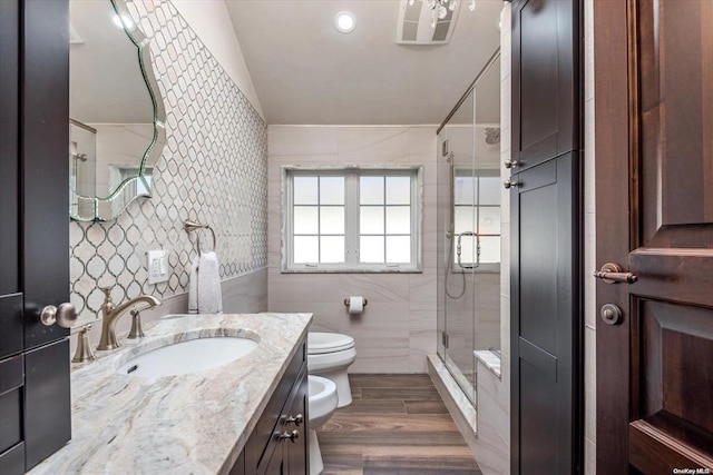 bathroom featuring hardwood / wood-style floors, vanity, a bidet, tile walls, and an enclosed shower