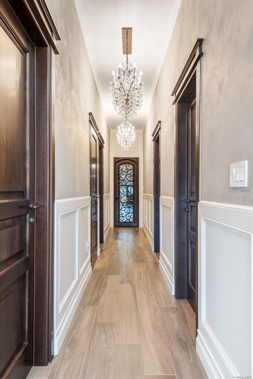 corridor with crown molding and a chandelier