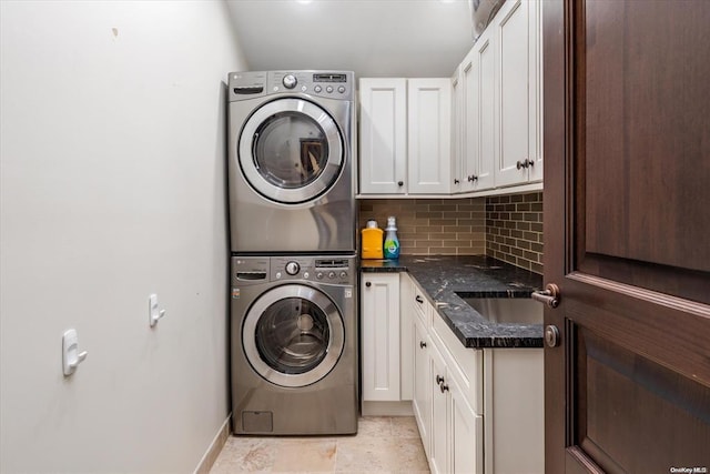 laundry room with stacked washer and dryer, cabinets, and sink