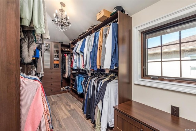 spacious closet featuring hardwood / wood-style flooring, lofted ceiling, and an inviting chandelier