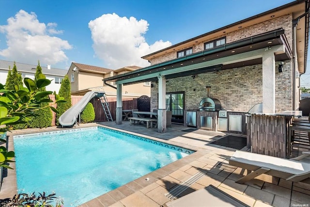 rear view of property featuring a fenced in pool, area for grilling, and a patio area