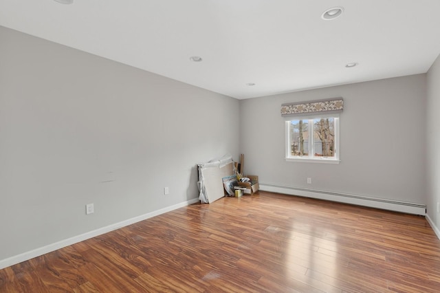 empty room featuring hardwood / wood-style floors and a baseboard heating unit