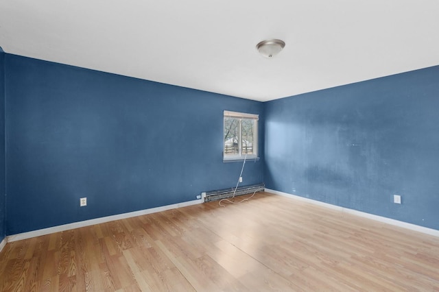 spare room with light wood-type flooring and a baseboard heating unit