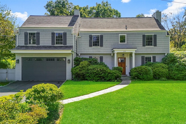 view of front of property with a garage, brick siding, a chimney, and a front yard