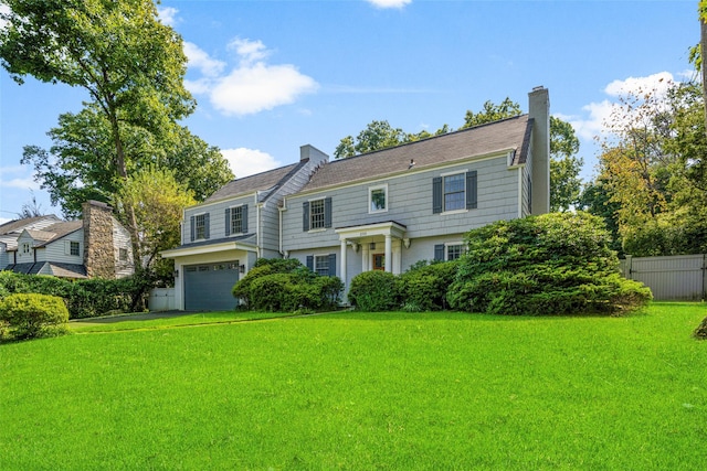 view of front of property featuring an attached garage, a chimney, fence, and a front yard