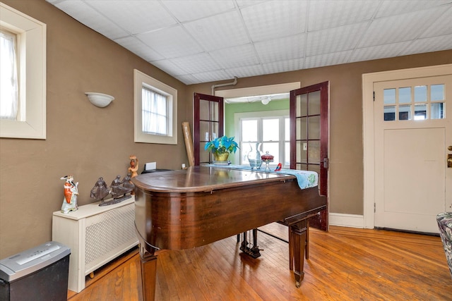 miscellaneous room featuring a wealth of natural light, french doors, a drop ceiling, and hardwood / wood-style floors