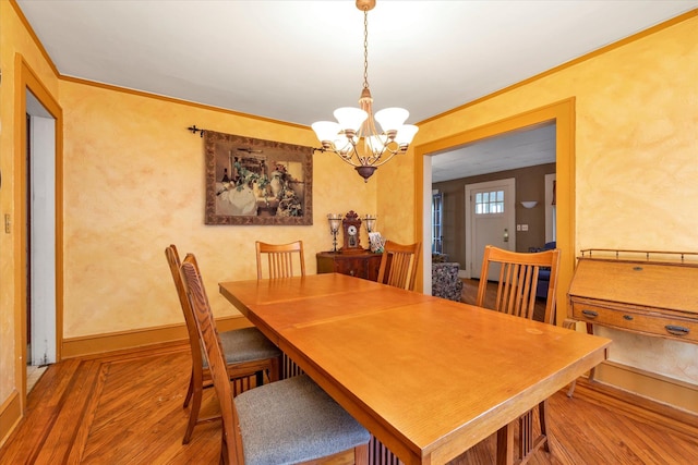 dining space featuring hardwood / wood-style flooring, a notable chandelier, and ornamental molding