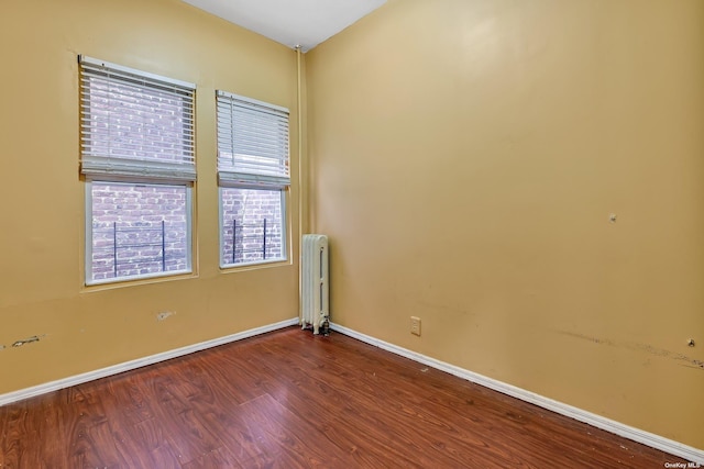 empty room with radiator heating unit and wood-type flooring