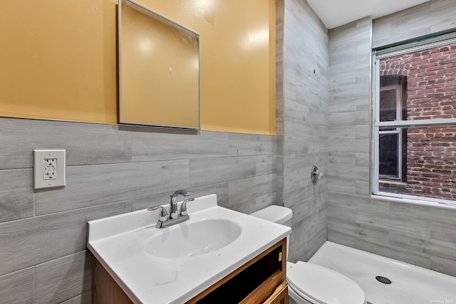 bathroom featuring a shower, vanity, tile walls, and toilet