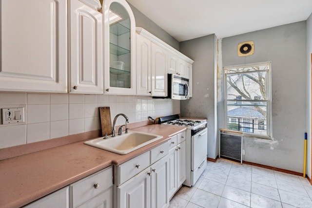 kitchen with white cabinetry, sink, tasteful backsplash, light tile patterned flooring, and white gas range oven