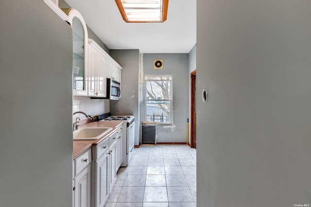 kitchen with white cabinetry, sink, light tile patterned floors, and appliances with stainless steel finishes