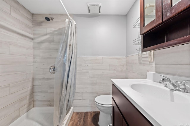 bathroom featuring a shower with curtain, toilet, vanity, tile walls, and hardwood / wood-style flooring