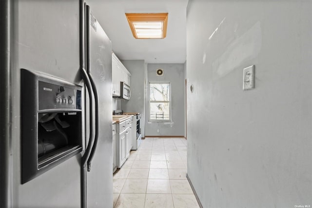 kitchen featuring white cabinets, light tile patterned flooring, and appliances with stainless steel finishes