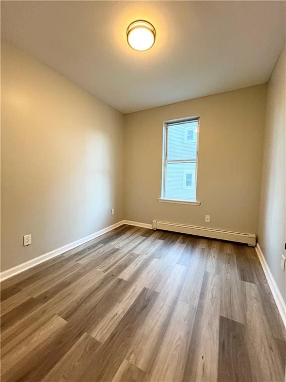 spare room featuring wood-type flooring and a baseboard radiator