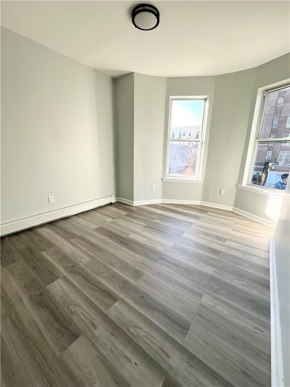 empty room featuring wood-type flooring and baseboard heating