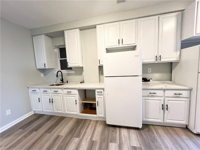 kitchen with white fridge, white cabinetry, sink, and light hardwood / wood-style flooring