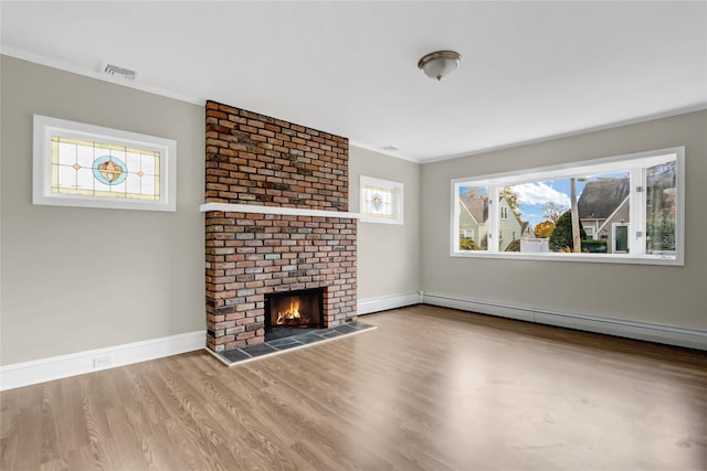 unfurnished living room featuring a healthy amount of sunlight, light hardwood / wood-style floors, a baseboard radiator, and a brick fireplace