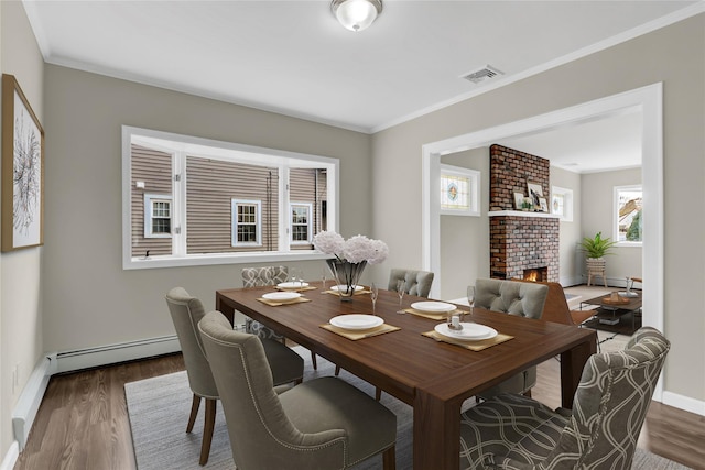 dining area with baseboard heating, a fireplace, dark wood-type flooring, and ornamental molding