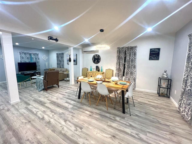 dining space with a wall mounted air conditioner and light hardwood / wood-style flooring