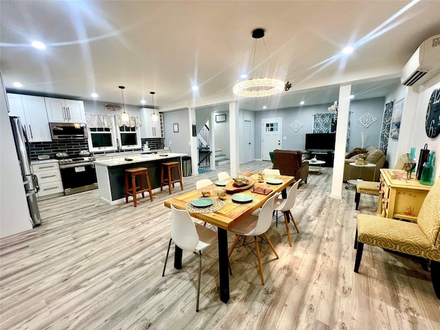 dining space with an AC wall unit, an inviting chandelier, ornamental molding, and light wood-type flooring