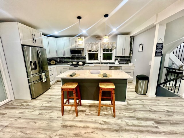 kitchen featuring a breakfast bar, a center island, light wood-type flooring, and stainless steel appliances