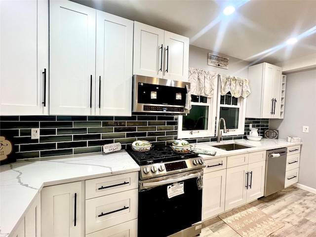 kitchen with sink, decorative backsplash, light hardwood / wood-style floors, light stone counters, and stainless steel appliances