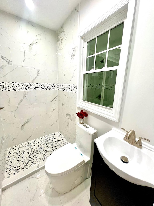 bathroom featuring tiled shower, vanity, and toilet