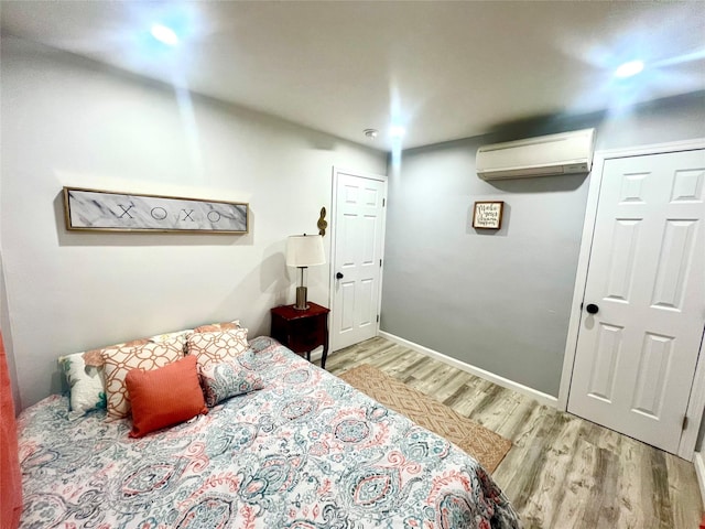 bedroom with light wood-type flooring and an AC wall unit