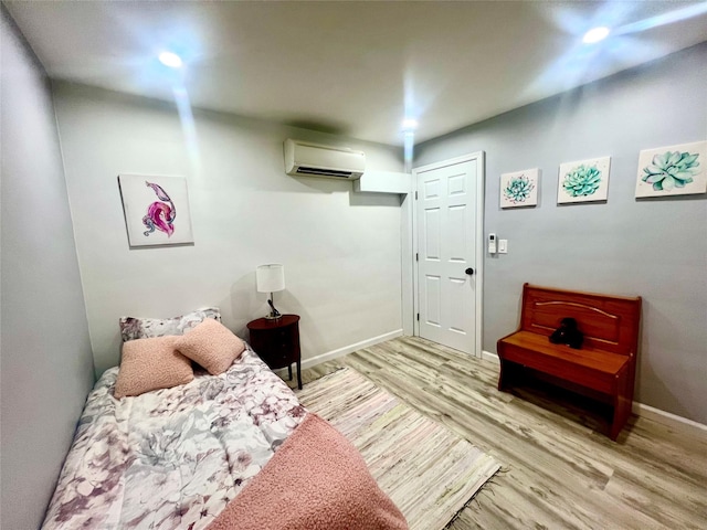 bedroom with a wall mounted air conditioner and light wood-type flooring