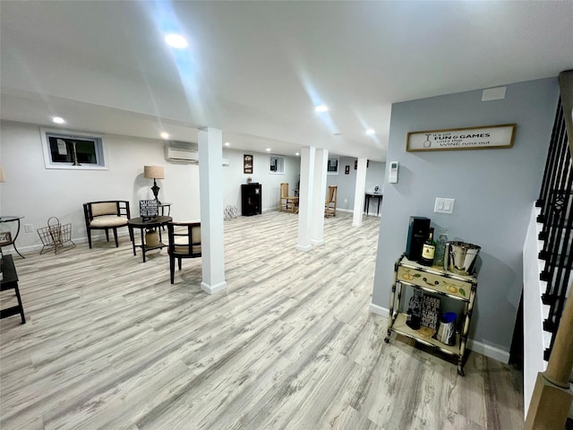 basement with a wall mounted air conditioner and light hardwood / wood-style floors