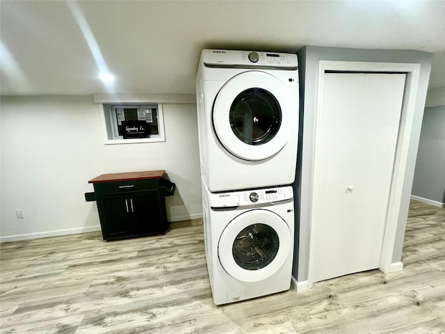 laundry room featuring light hardwood / wood-style flooring and stacked washing maching and dryer