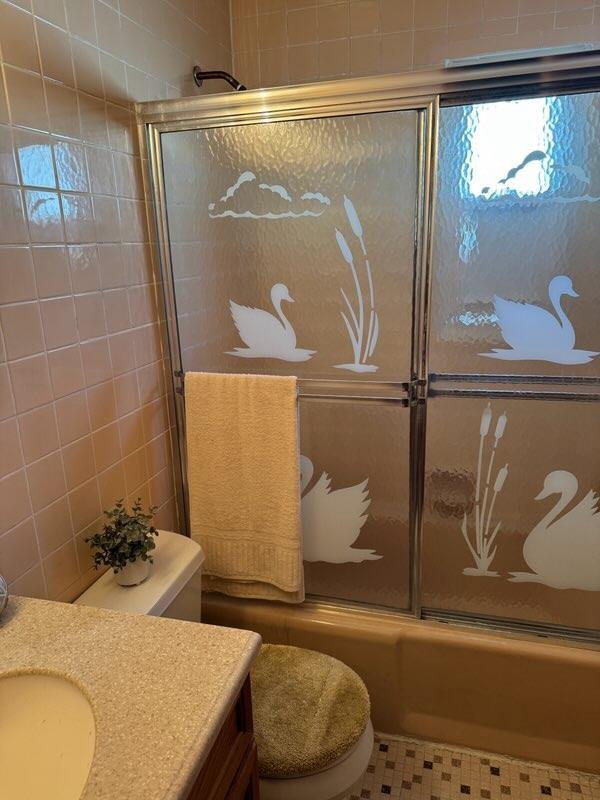 full bathroom featuring tile patterned floors, toilet, vanity, and combined bath / shower with glass door