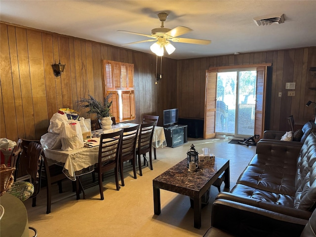 living room featuring ceiling fan and wood walls