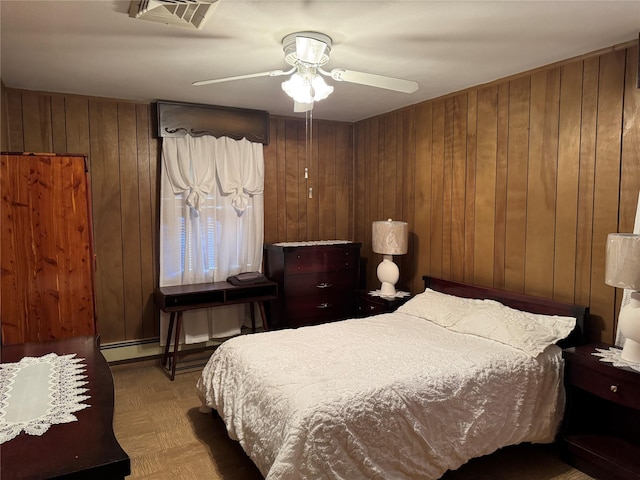 bedroom featuring wood walls, ceiling fan, and a baseboard radiator