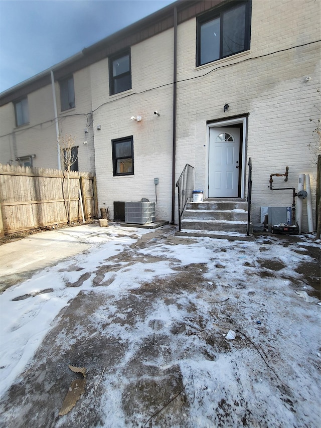 snow covered back of property featuring cooling unit