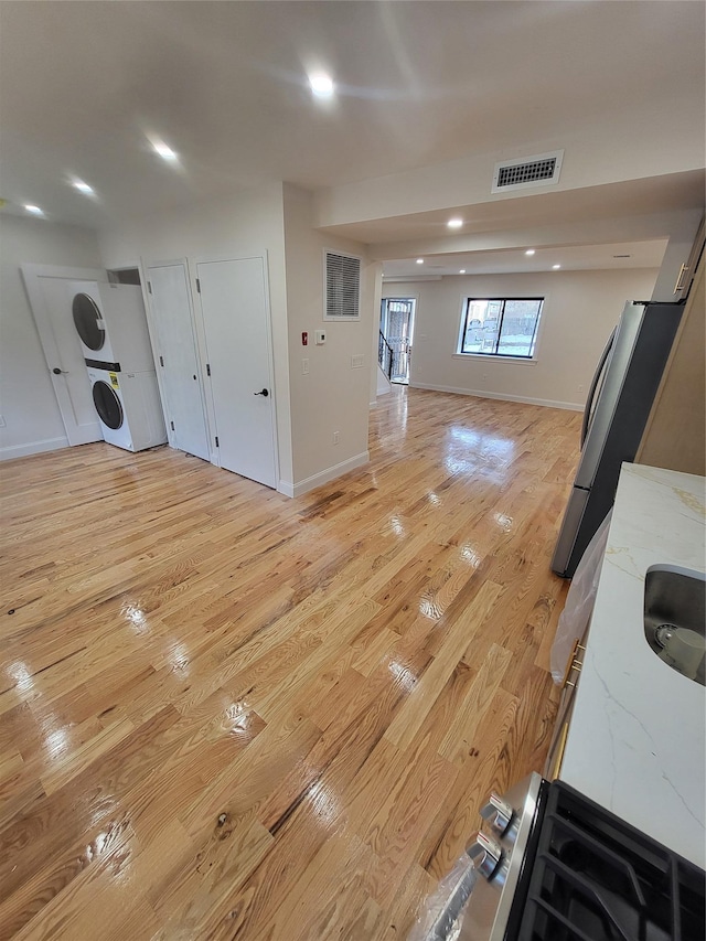 living room featuring stacked washer and dryer and light hardwood / wood-style flooring