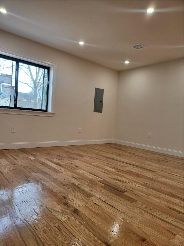 empty room with electric panel and light hardwood / wood-style floors