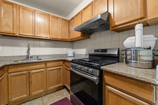 kitchen featuring light stone countertops, decorative backsplash, gas stove, ventilation hood, and sink