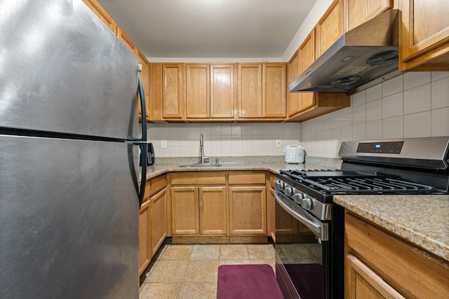 kitchen featuring light stone countertops, sink, tasteful backsplash, extractor fan, and appliances with stainless steel finishes