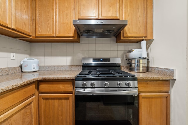 kitchen with gas stove, backsplash, light stone countertops, and exhaust hood